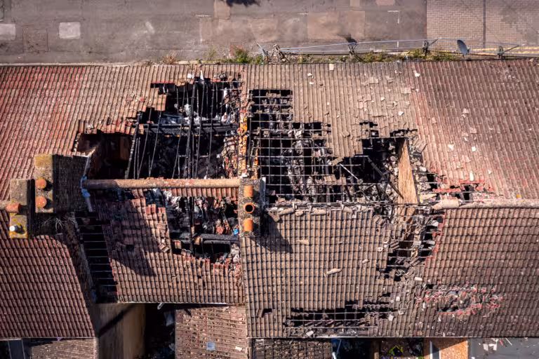 Aerial view of a building with a large, charred hole in the roof, exposing damaged beams and severe fire destruction—ideal for showcasing roof repair after storm damage or comprehensive storm damage restoration needs.