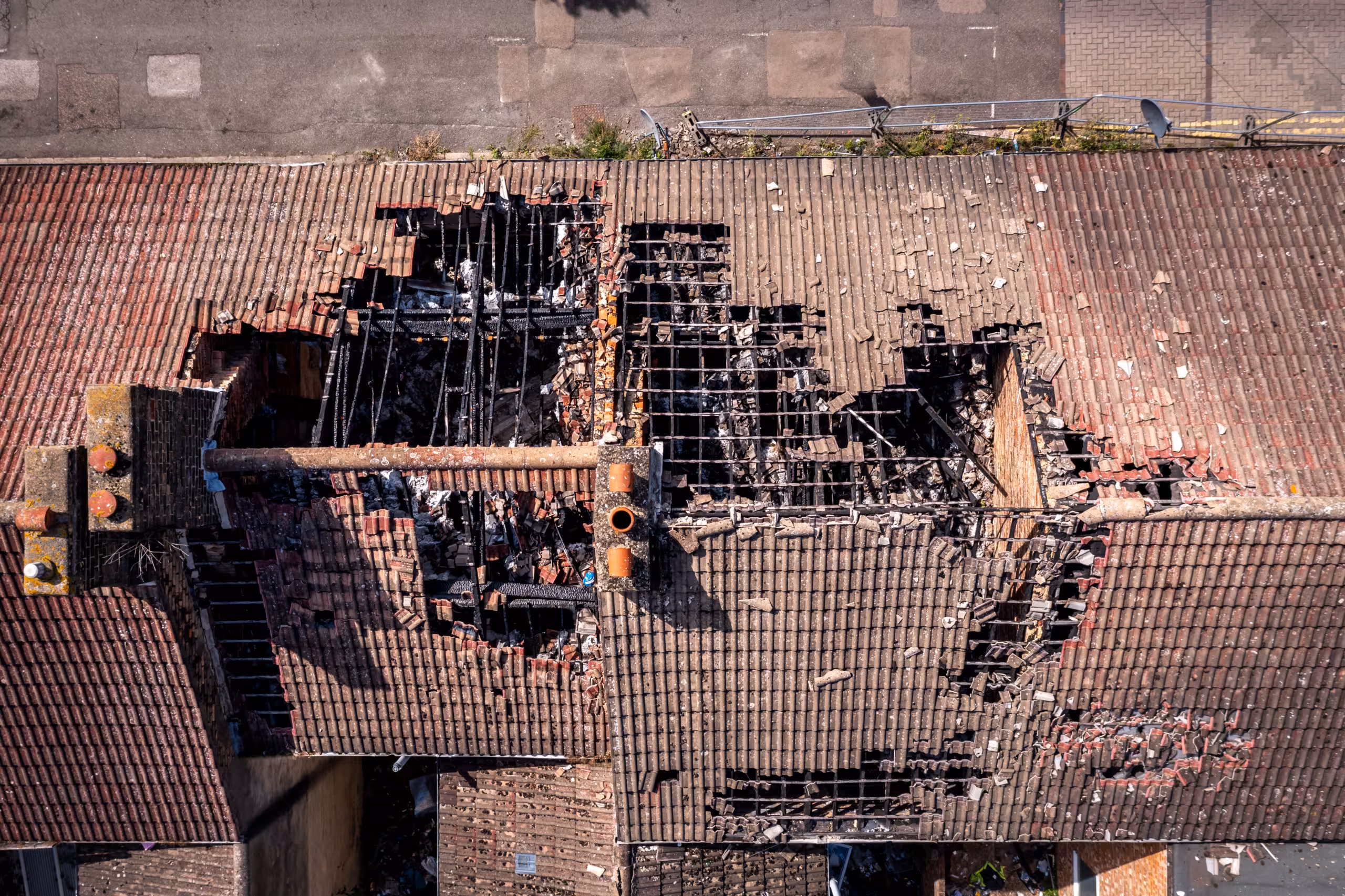 Aerial view of a building with a large, charred hole in the roof, exposing damaged beams and severe fire destruction—ideal for showcasing roof repair after storm damage or comprehensive storm damage restoration needs.